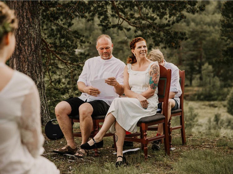 Brudeparet sitter på benker ute i naturen.