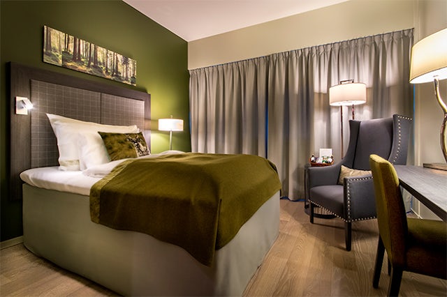 Bilde av et komfortabelt hotellrom med enkeltseng, en lenestol og et lite skrivebord.